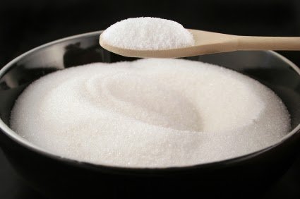 black bowl of plain white sugar with a wooden spoonful over it